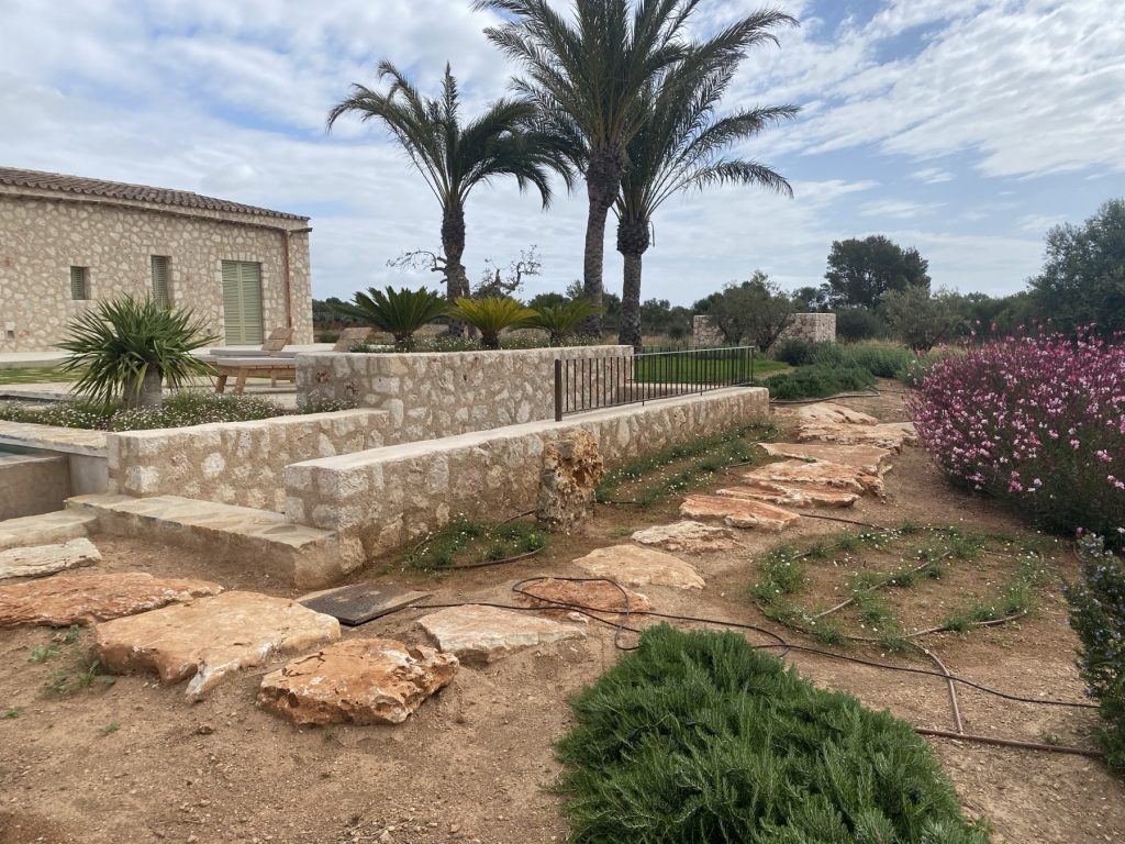 Natural stone wall with terrace, pool and stone path in a Mallorcan garden